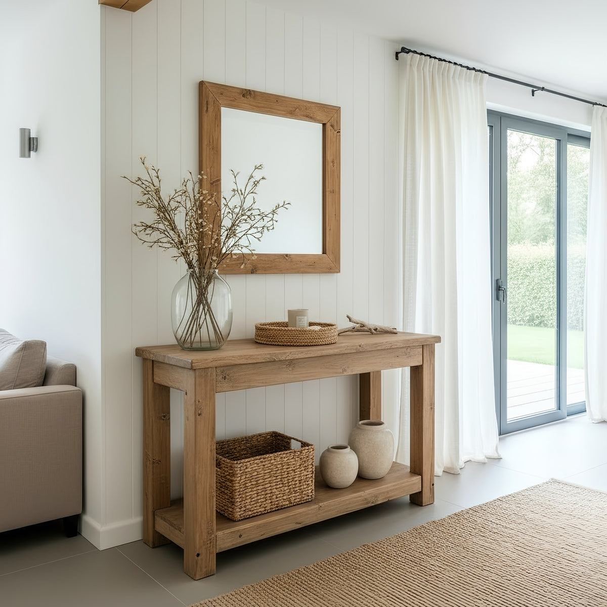 Light oak solid wood console table polo with lower shelf holding woven basket and ceramic vases