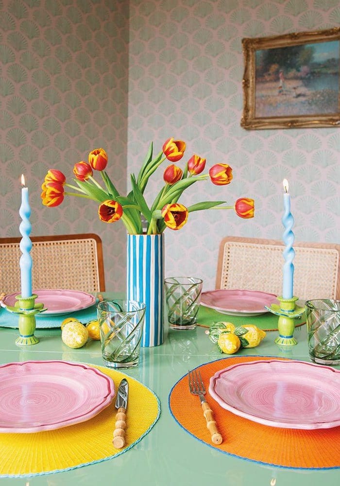 A tall vase with blue and white stripes holds orange tulips next to poolside gossip green acrylic tumbler set of 6