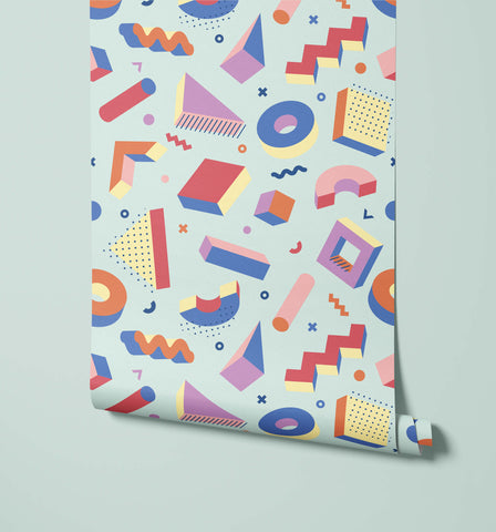 A roll of pop wallpaper with colorful geometric shapes in pink blue orange and yellow on a light mint background