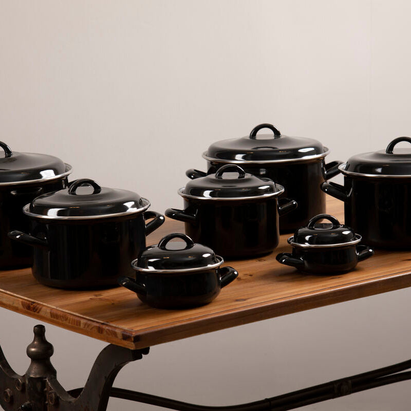 Set of black enamel 12cm casserole dishes with silver rims and loop handles on a wooden table