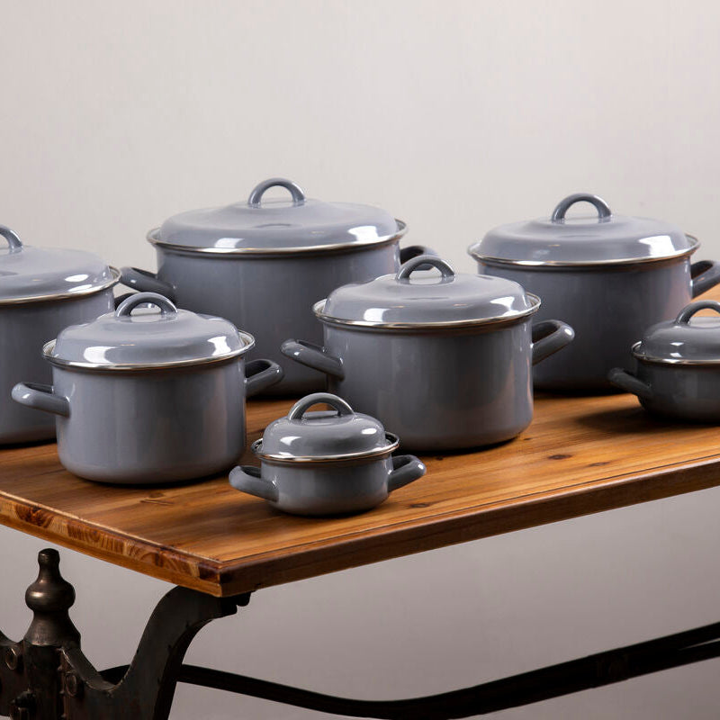 Set of porter grey enamel 22cm casserole dishes with matching lids and loop handles on a wooden table