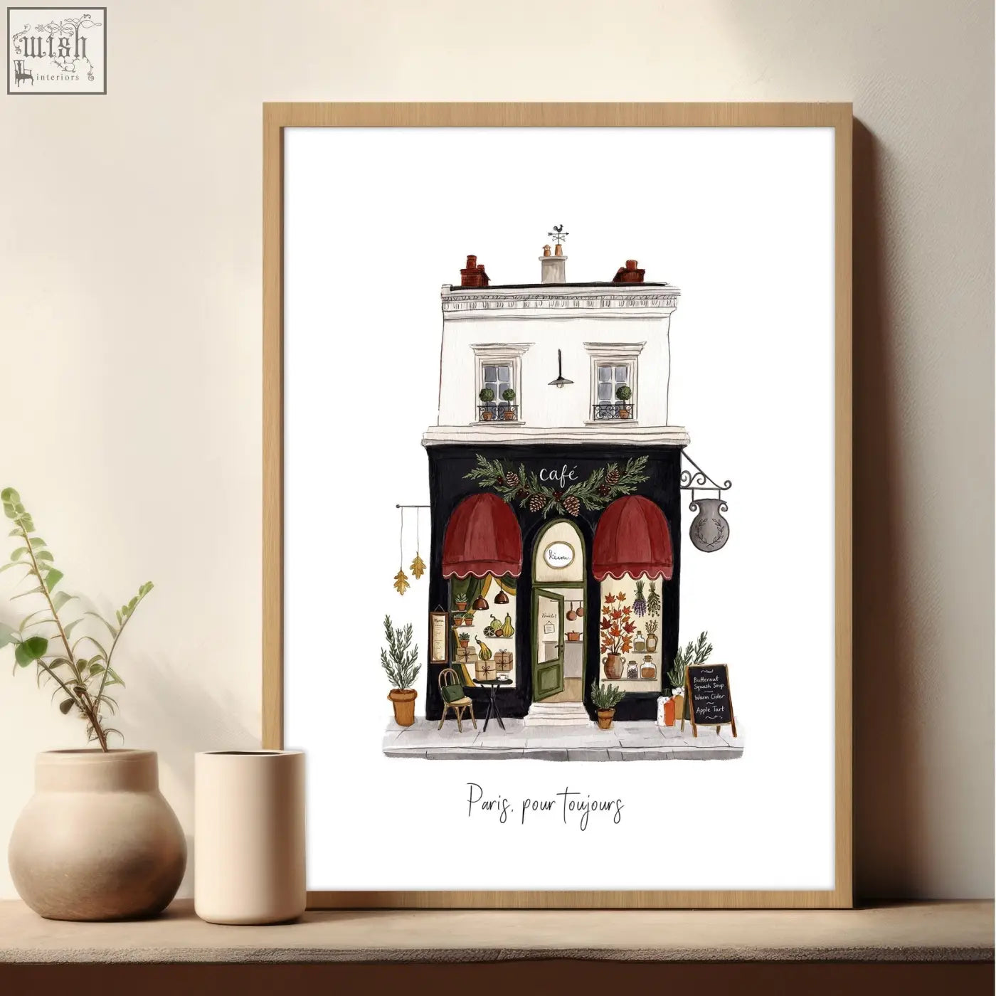 A framed paris street scenes wall art with red awnings and greenery in a light wood frame from the pour toujours set