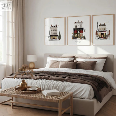 Beige upholstered bed with layered white and brown bedding next to street scenes pour toujours wall art set of 3