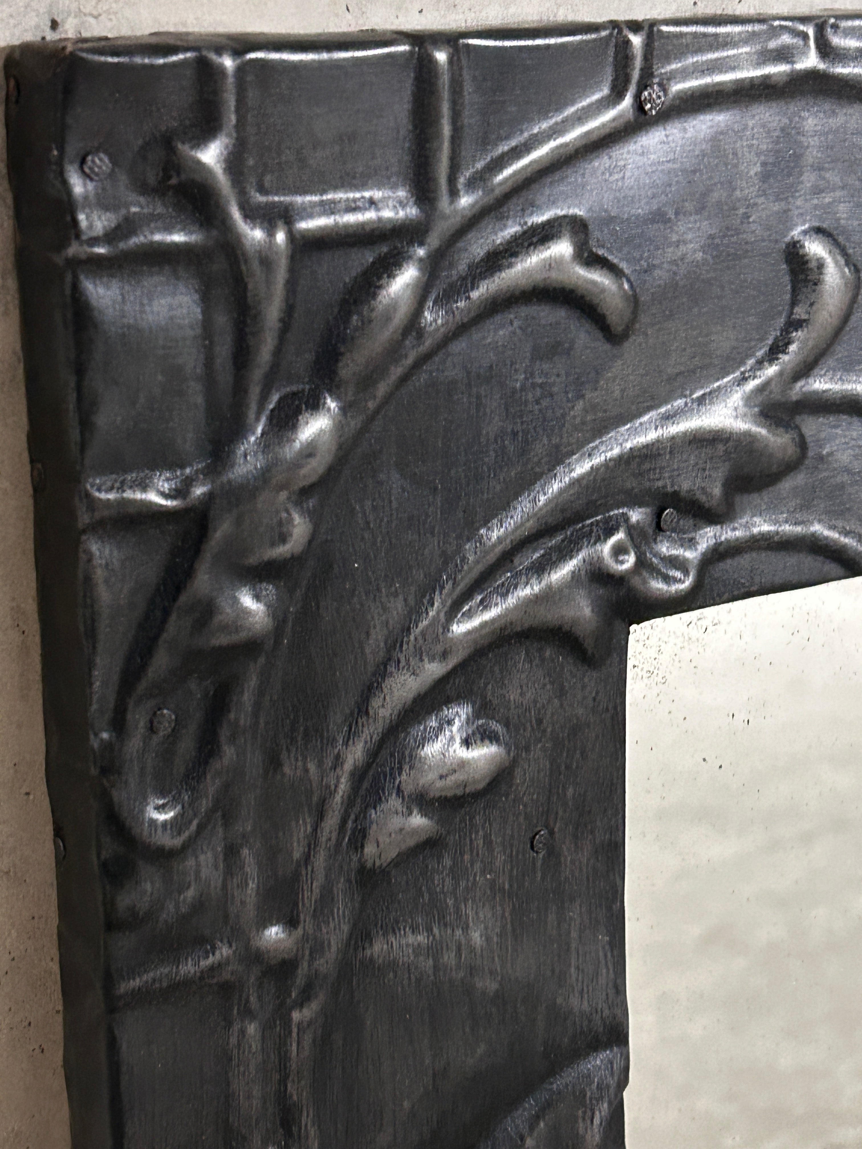 Dark metallic pressed tin ceiling mantel with intricate leaf and vine relief detailing for fireplace decor