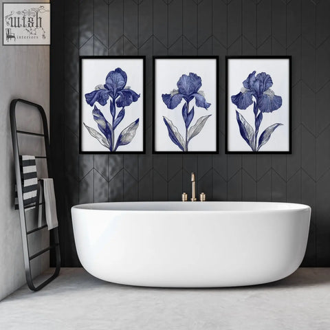 Three framed blue iris botanical wall art prints hang above a white freestanding bathtub for bathroom decor