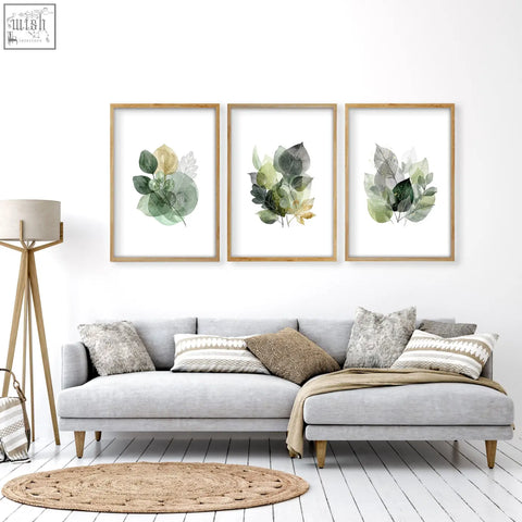 Three framed living room botanical prints with green and gold-tone watercolor leaves in light wood frames set of 3