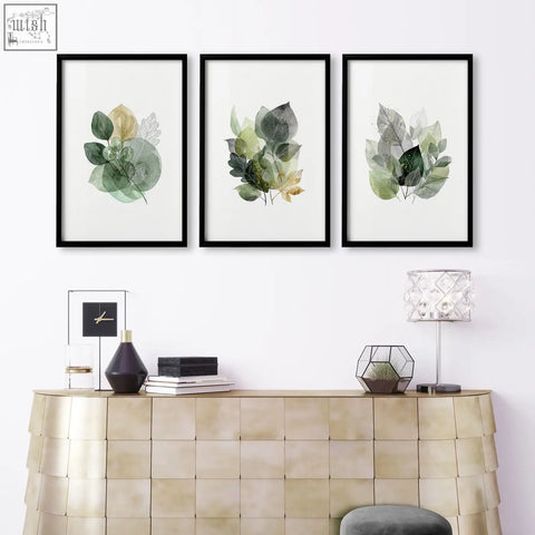 Set of three living room botanical prints with green and gold-tone layered leaf illustrations in black frames