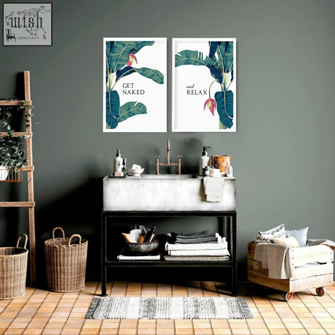 Two framed tropical wall prints with green banana leaves pink flowers and get naked and relax text for bathroom walls
