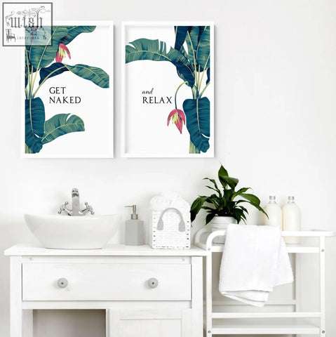 Two framed tropical wall art prints with green banana leaves and pink blossoms for bathroom walls above vanity