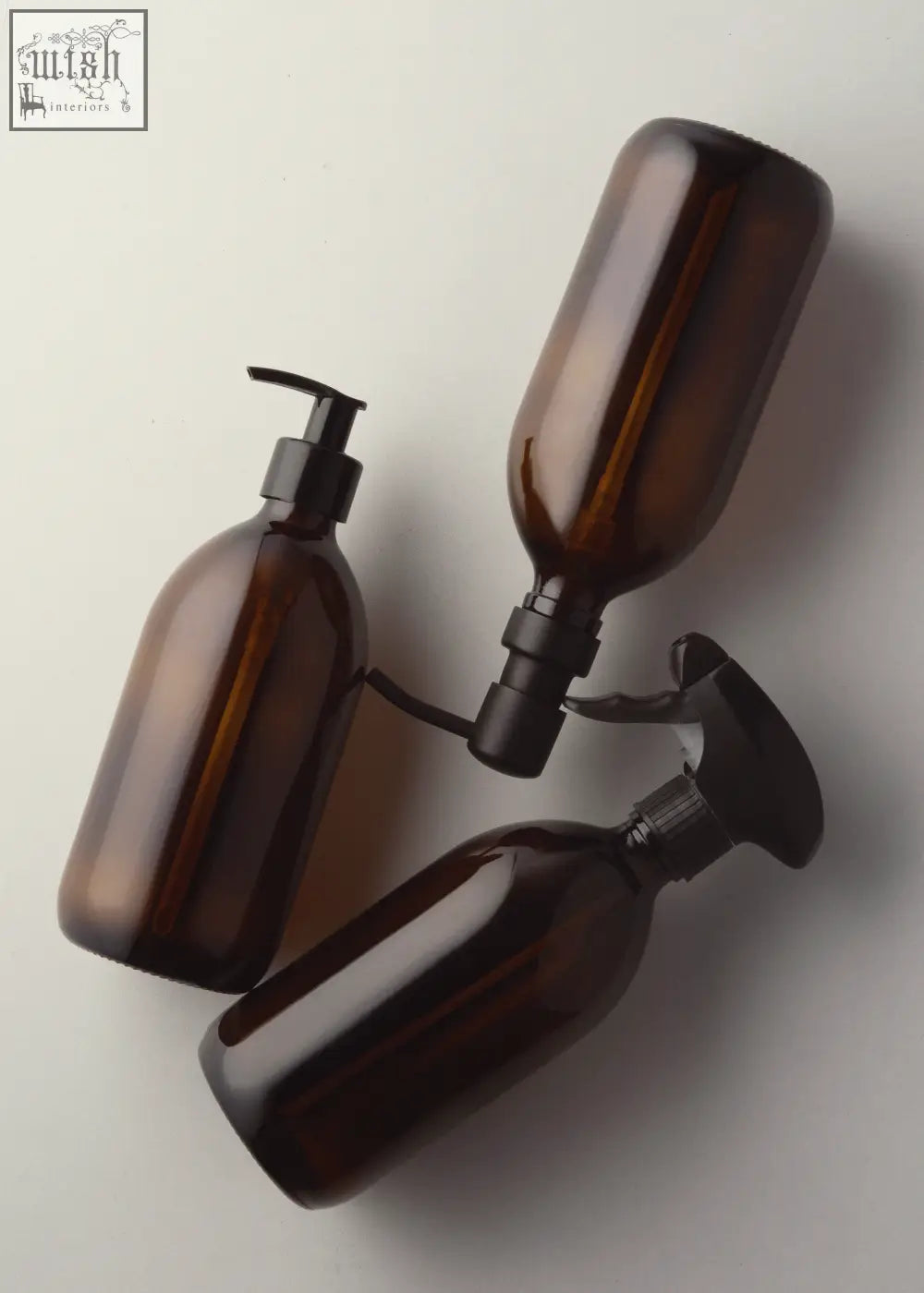 Three amber glass pump bottle dispensers with black pump and spray nozzles for easy liquid dispensing