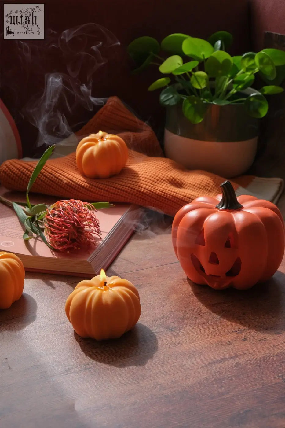 Orange ceramic jack o lantern cone burner with carved face and lit wick for burning incense cones