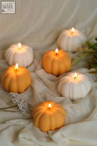 Orange and white pumpkin shaped wax candles with lit wicks perfect for pumpkin spice fall decor