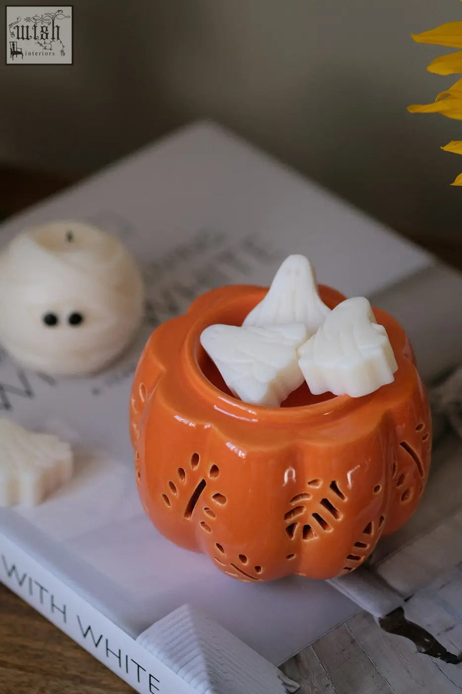 Orange ceramic pumpkin wax melt burner with decorative cut-outs and white star-shaped pumpkin spice wax melts inside