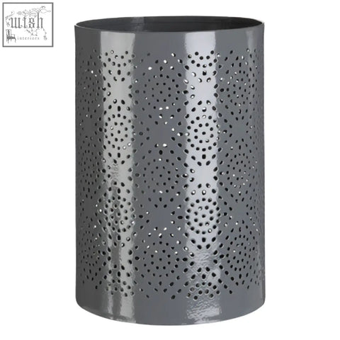 Grey candle holder with punched metal pattern featuring circular perforations for large candle use