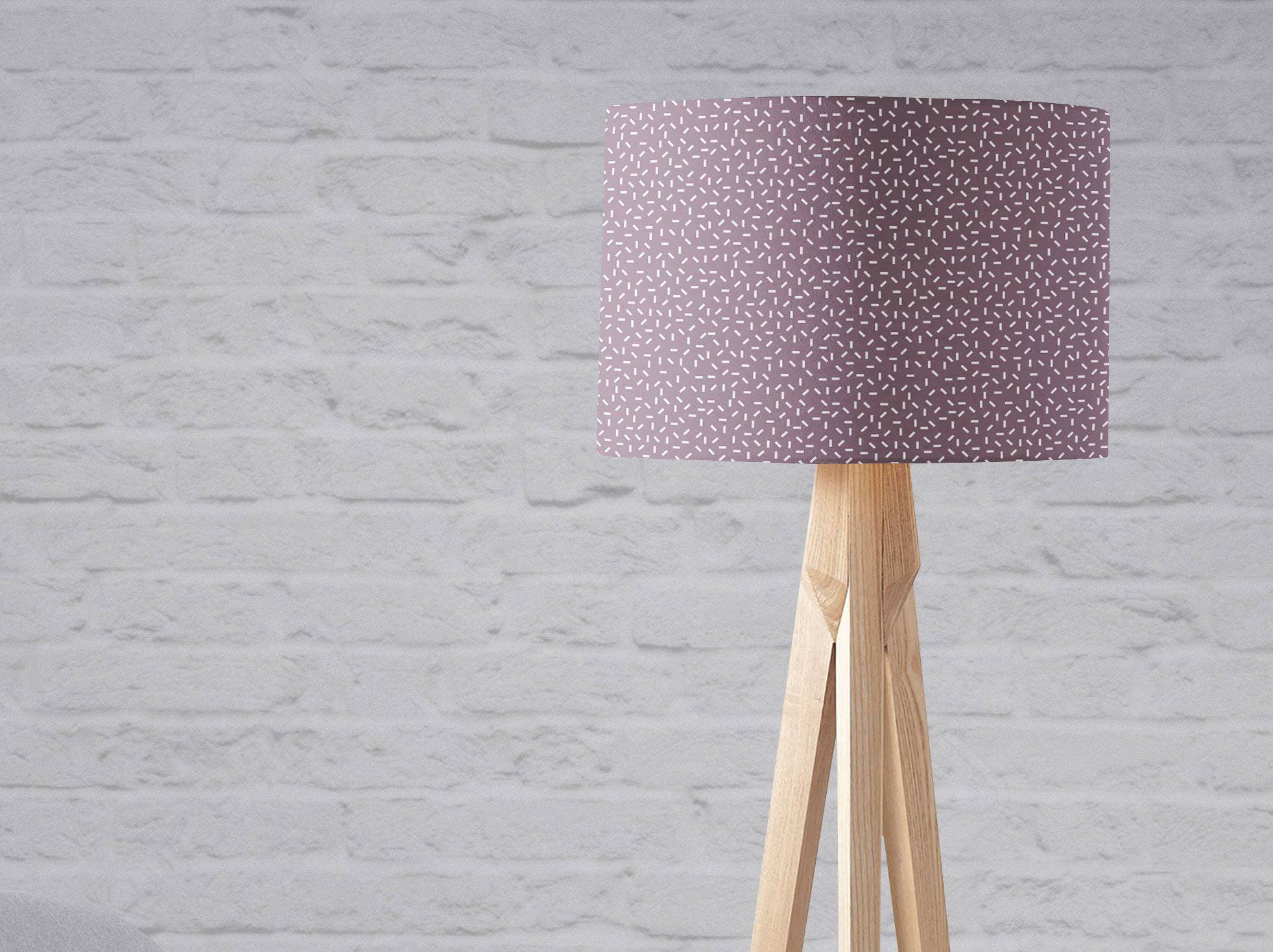 Purple lampshade table lamp with modern line design and subtle white speckled pattern on light wood tripod base