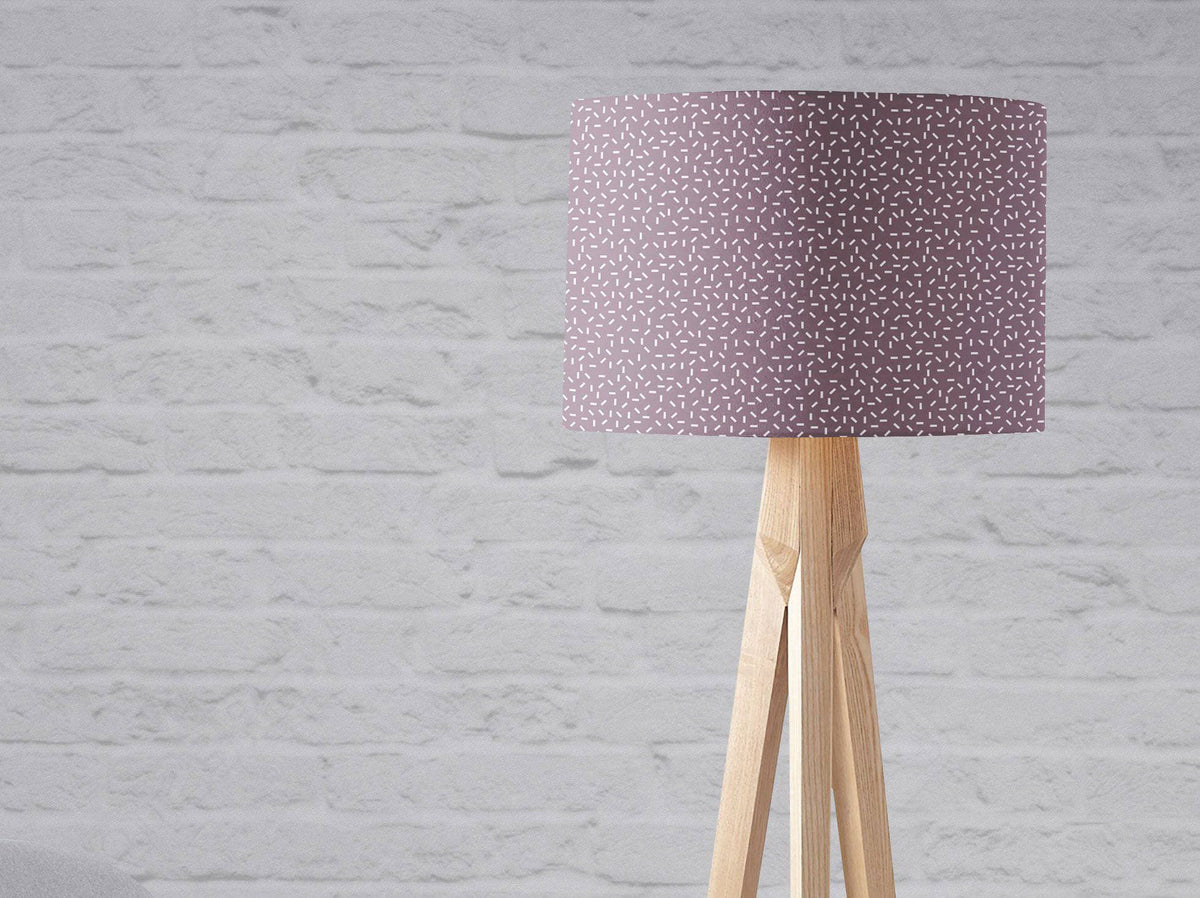 Purple lampshade table lamp with modern line design and subtle white speckled pattern on light wood tripod base