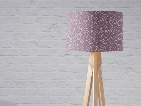 Purple lampshade table lamp with modern line design and subtle white speckled pattern on light wood tripod base