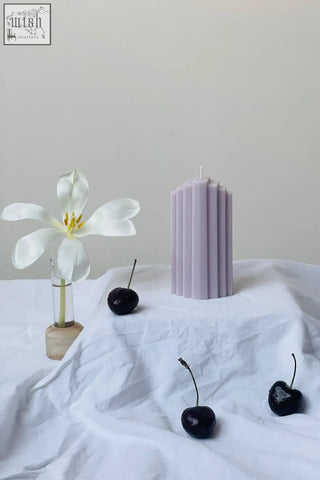 A tall lavender pyramid sculpted candle with vertical ridges perfect for home decor and ambiance