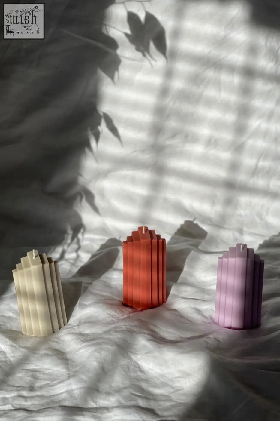 Pyramid sculpted candle with three ribbed candles stacked vertically in cream terracotta and lavender hues