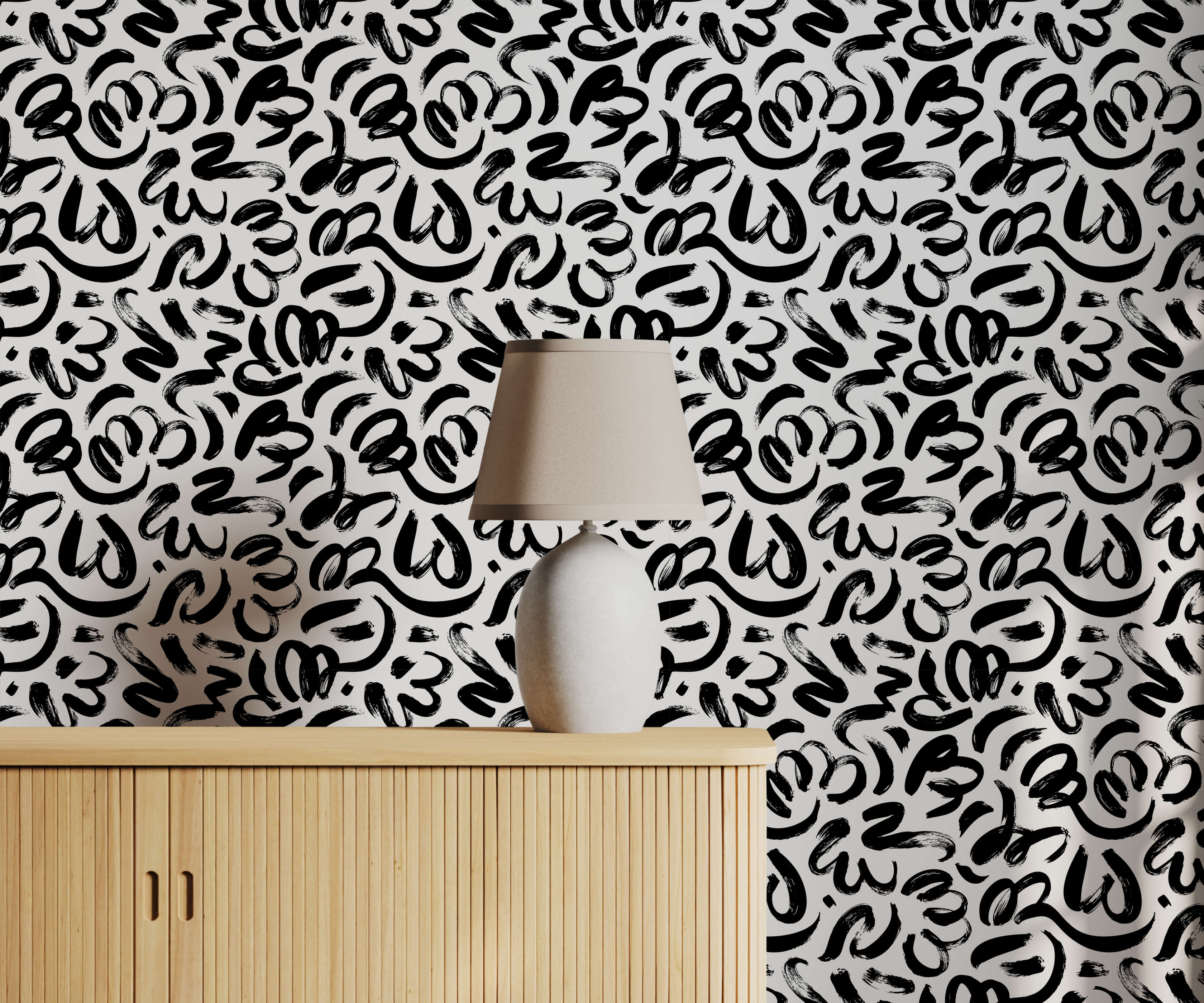 A sleek white ceramic quake table lamp with beige fabric shade on light wood cabinet with brushstroke wallpaper background