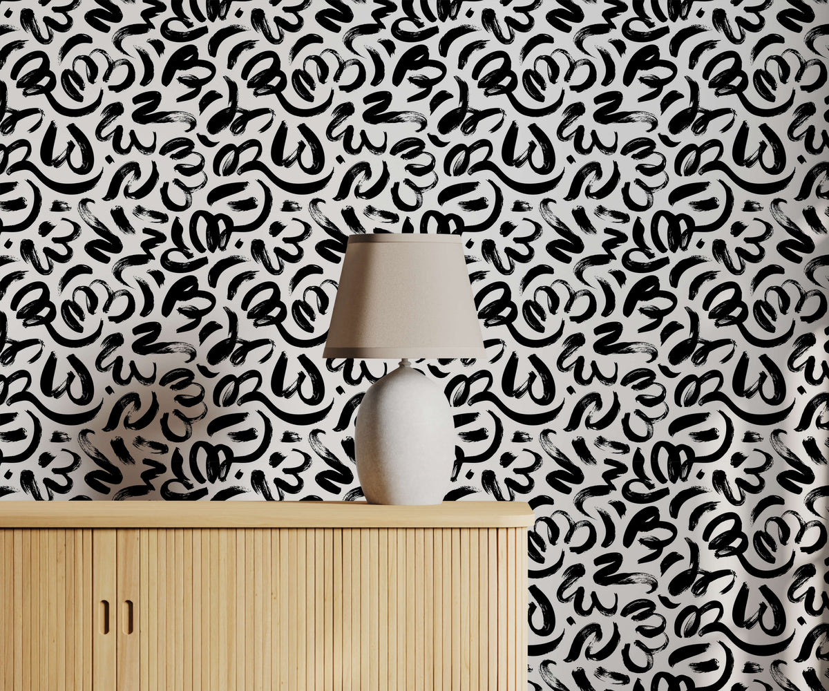 A sleek white ceramic quake table lamp with beige fabric shade on light wood cabinet with brushstroke wallpaper background