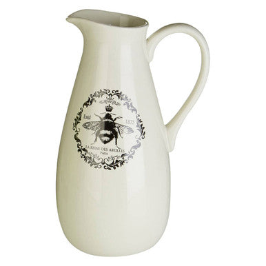 Cream-colored ceramic queen bee pitcher with black bee emblem and ornate scrollwork detail