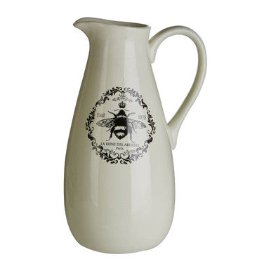 Cream-colored ceramic queen bee pitcher with a short spout and black and white bee emblem with ornate detailing