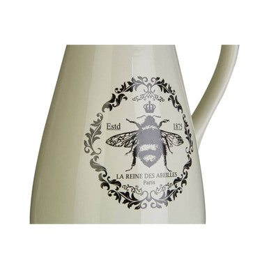 Cream-colored ceramic queen bee pitcher with black and white bee emblem and ornate decorative border