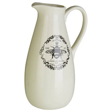 Cream-colored ceramic queen bee pitcher with short spout and black and white bee emblem with decorative details