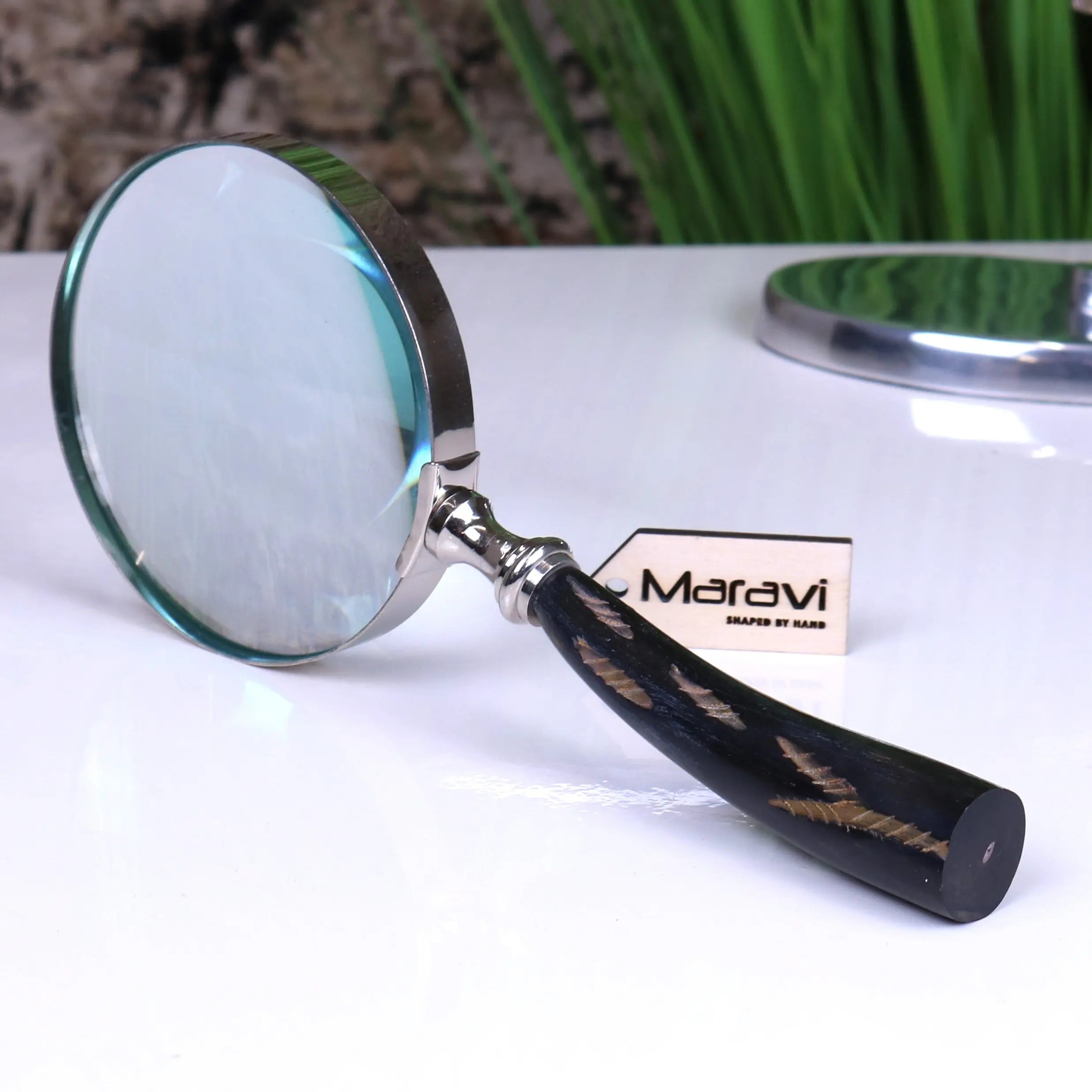 Handcrafted rada magnifying glass with a polished silver frame and black handle with golden feather inlays