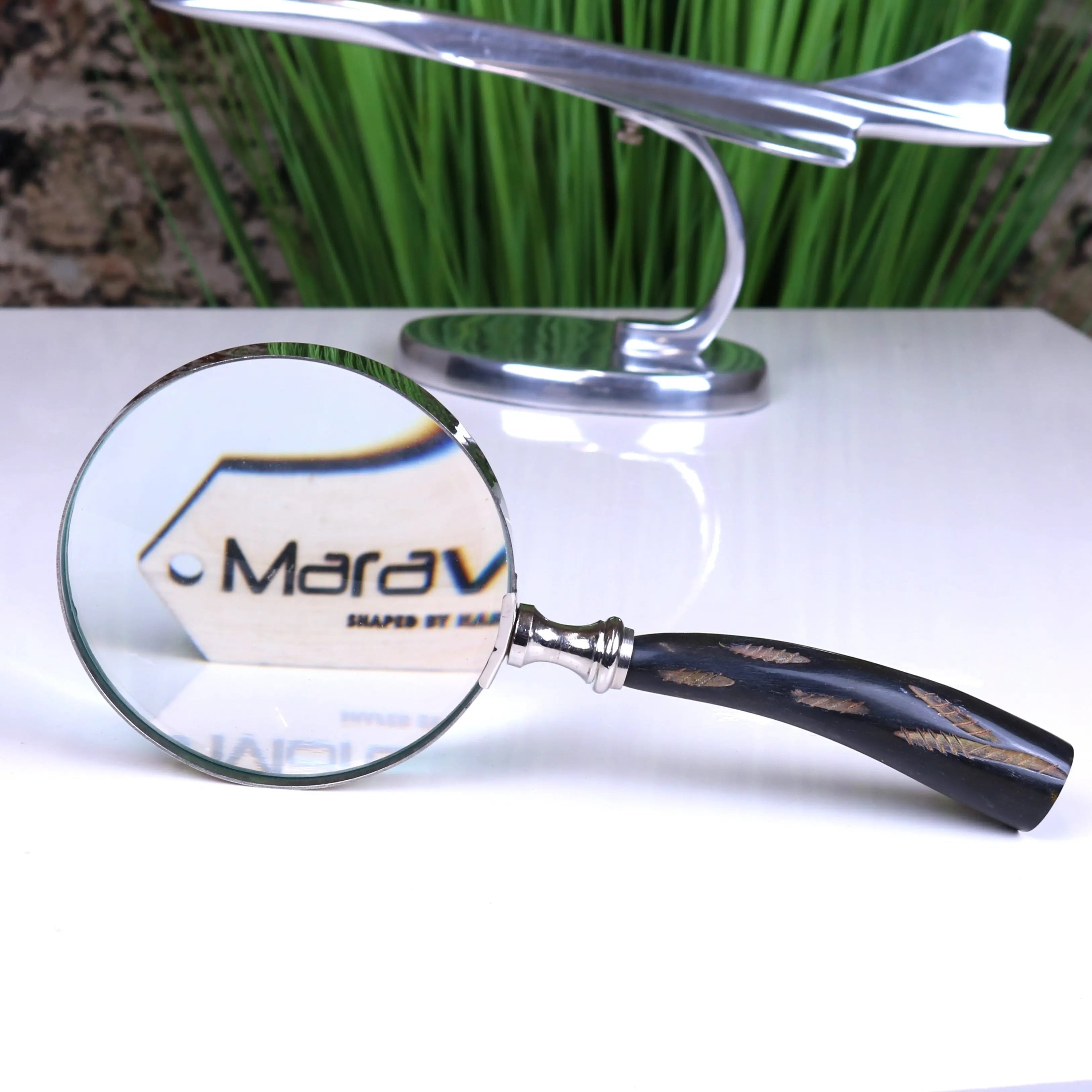 A rada magnifying glass with a sleek silver frame and elegant black handle featuring gold feather inlays