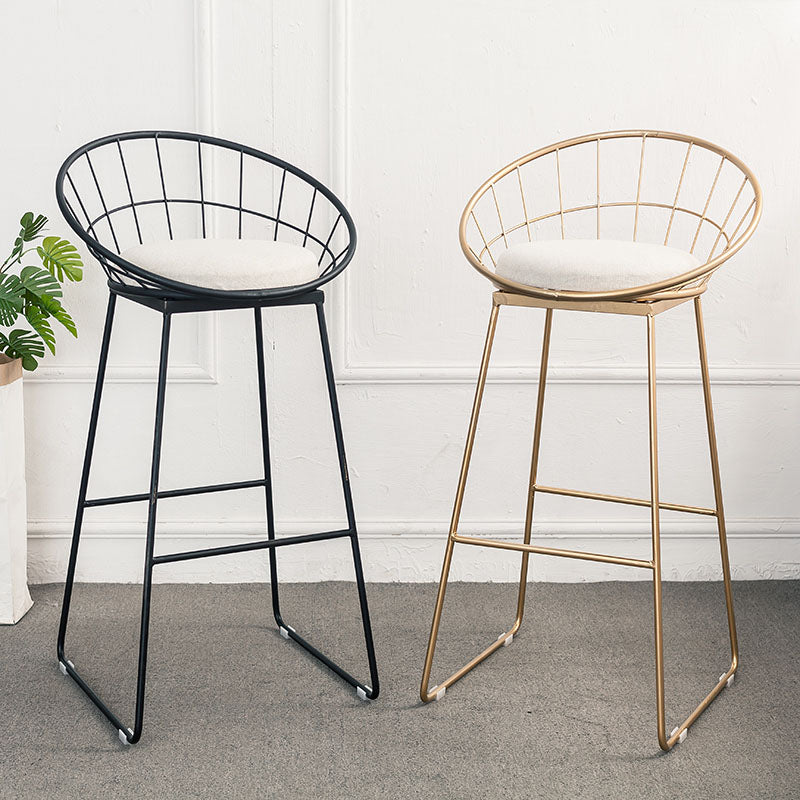 Two rafael sphere bar stools with wireframe metal frames in black and gold and cushioned white seats