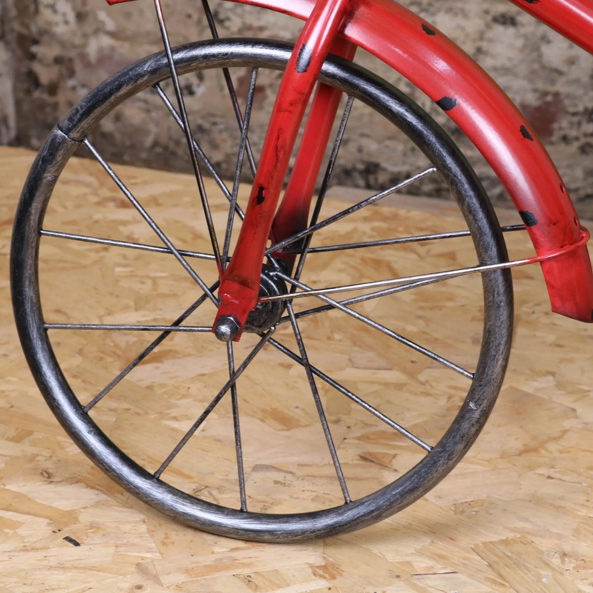 Red-painted vintage style bicycle wheel with black metal rim and spokes on rahi vintage style tricycle ornament