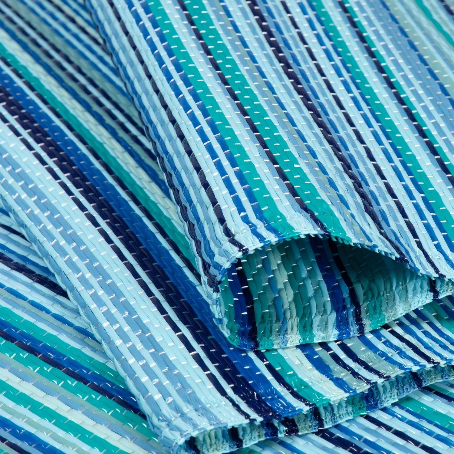 A woven plastic rainbow outdoor rug with teal navy and light blue stripes perfect as an outdoor rug blue option