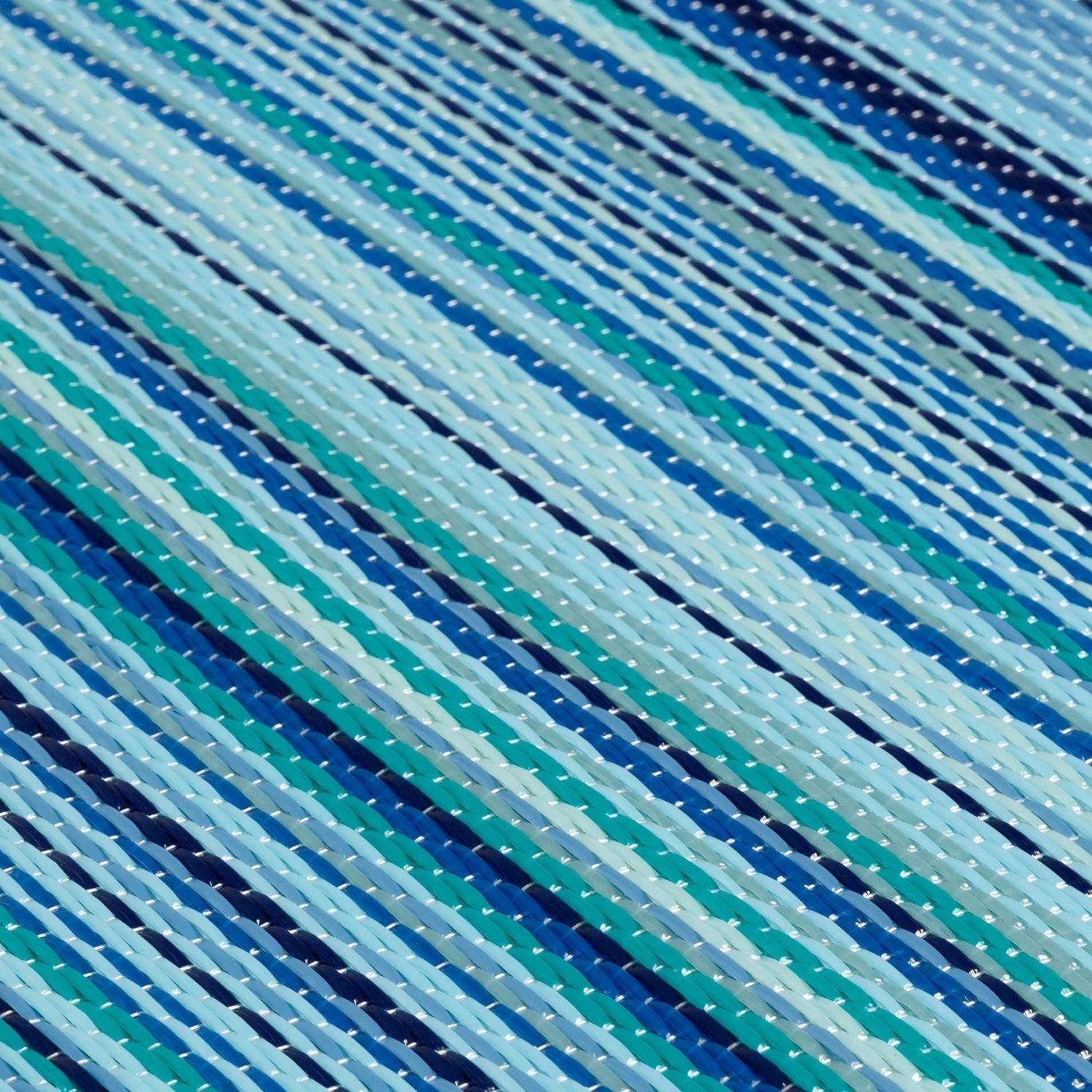 A woven rainbow outdoor rug blue with diagonal stripes in shades of blue teal and white perfect for outdoor use