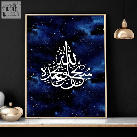 A framed ramadan decoration wall art print with white islamic calligraphy on deep blue cosmic background in gold frame