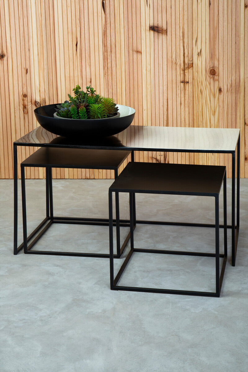 Set of three nested black metal coffee tables with minimalist frames and glass tops next to a white ombre bowl