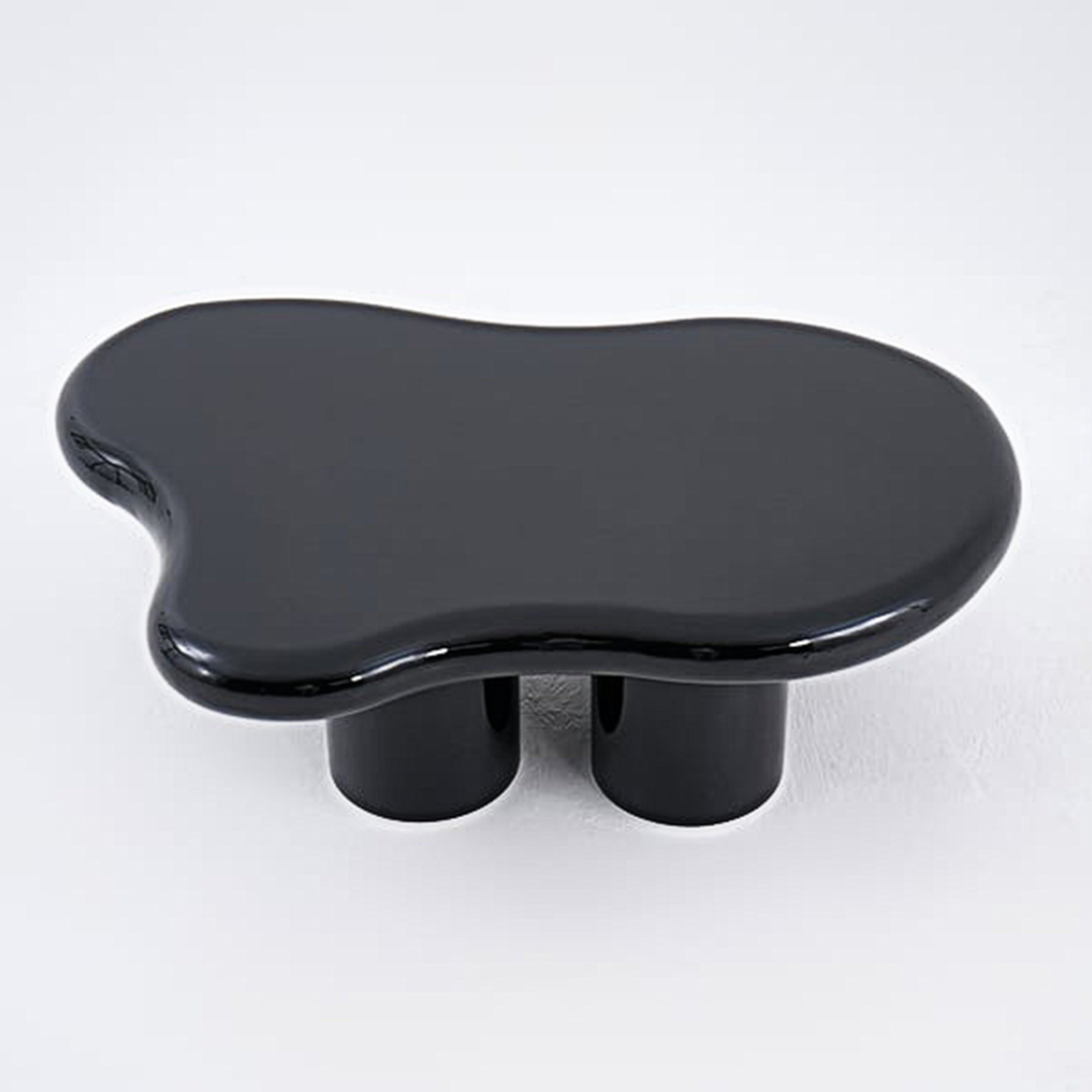 Black glossy ceramic ramy coffee table with organic flowing shape and two cylindrical legs for living room use