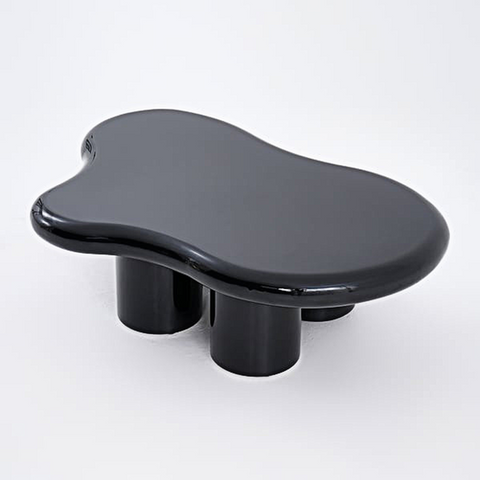 A sleek glossy black ceramic ramy coffee table with an organic amoeba top and sturdy cylindrical legs