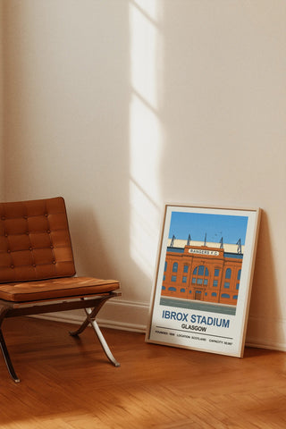 A framed stadium print of rangers ibrox stadium featuring a stylized illustration with blue sky and orange brick architecture