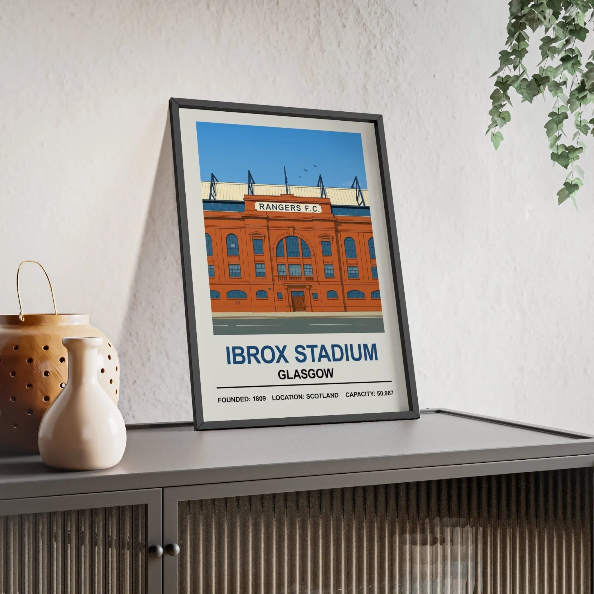 A framed stadium print of rangers ibrox stadium showing the orange brick facade with blue accents and white text