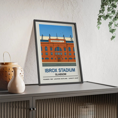 A framed stadium print of rangers ibrox stadium showing the orange brick facade with blue accents and white text