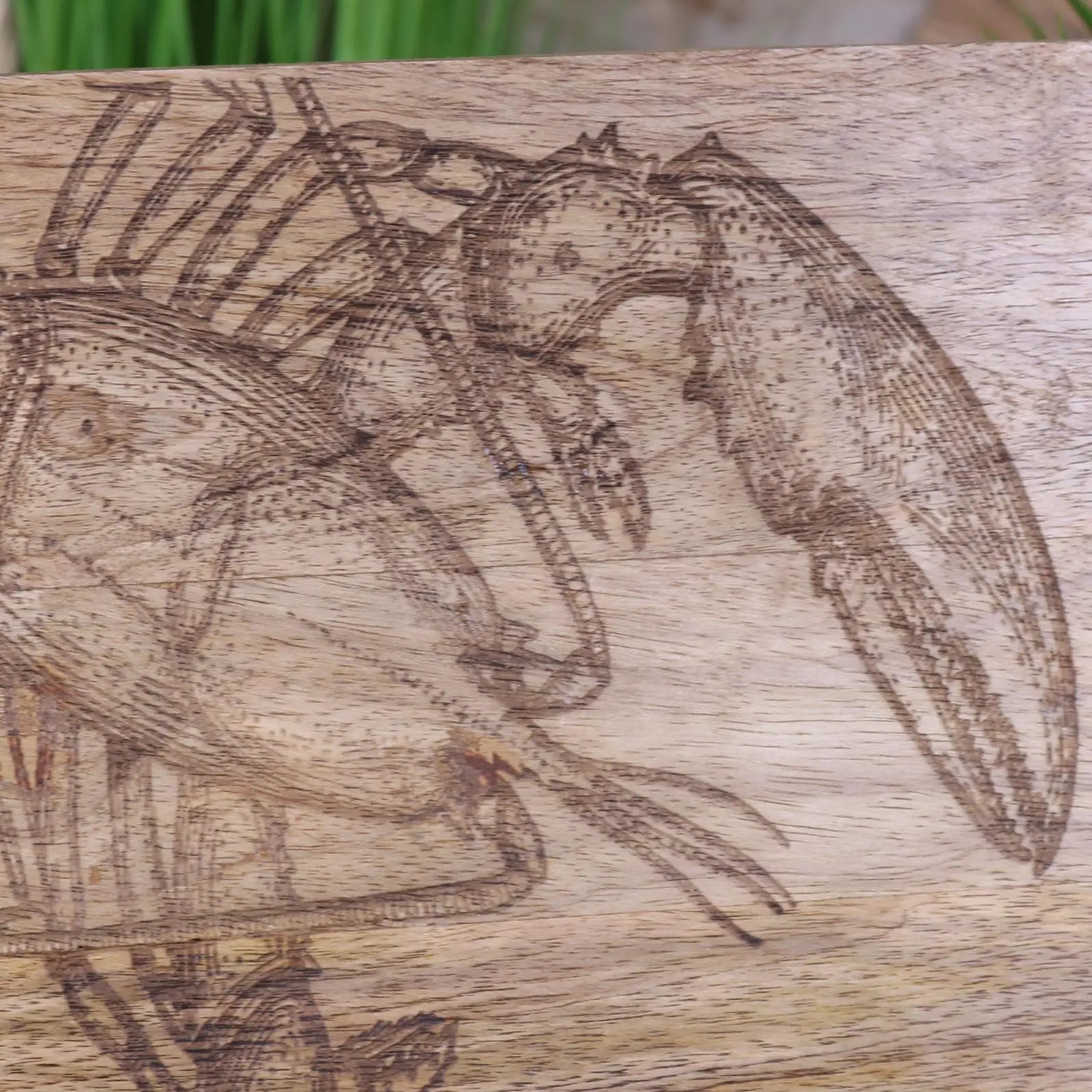 A light brown wooden Rateka lobster fish serving platter board with a detailed etched lobster design