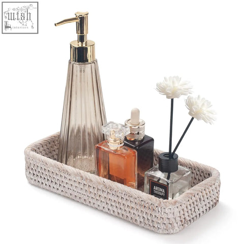 Beige woven rattan bathroom vanity tray with gold soap dispenser and glass bottles for toilet tank storage and decor