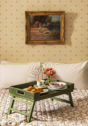 Green rattan breakfast tray with foldable design holding breakfast items and flowers for easy serving