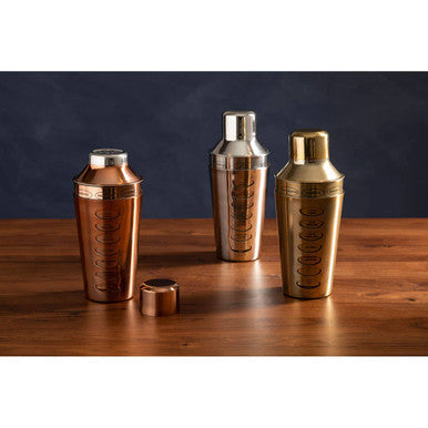 Three metallic cocktail shakers with rose gold, gold, and silver tones featuring engraved circular patterns for mixing drinks