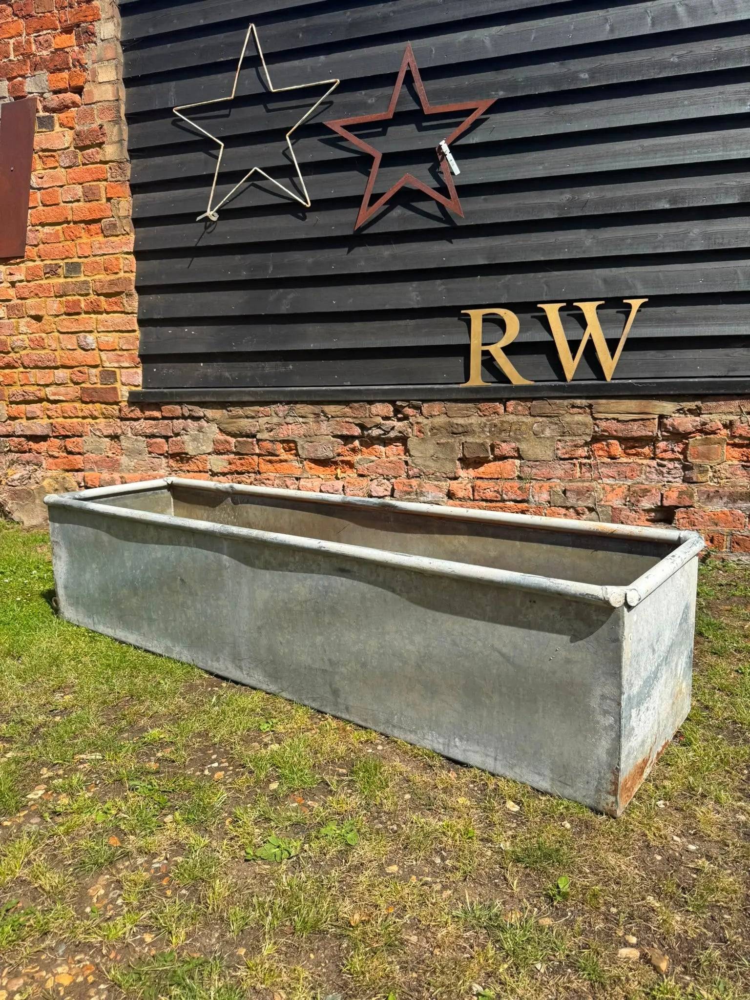 Long rectangular galvanised trough planter with internal strengthening bar and weathered metal for raised flower bed