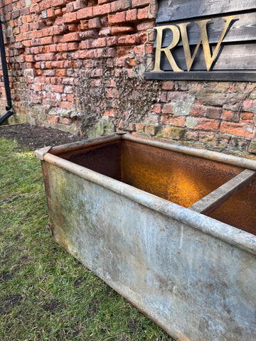 Rust-stained galvanized metal trough planter with weathered industrial look for raised bed planting trees shrubs and herbs