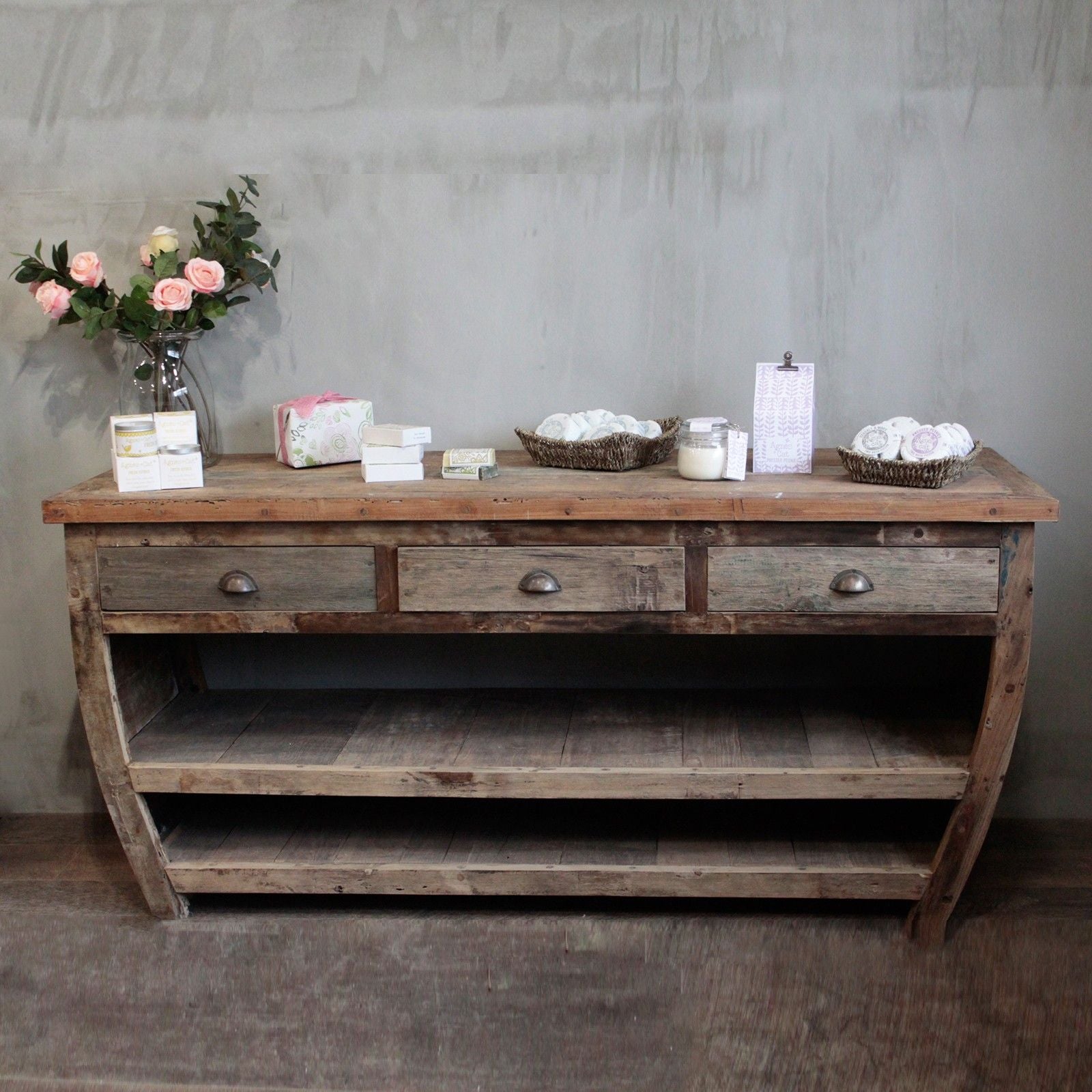Rustic recycled teak wood console table with three drawers and open shelves in weathered finish and metal handles