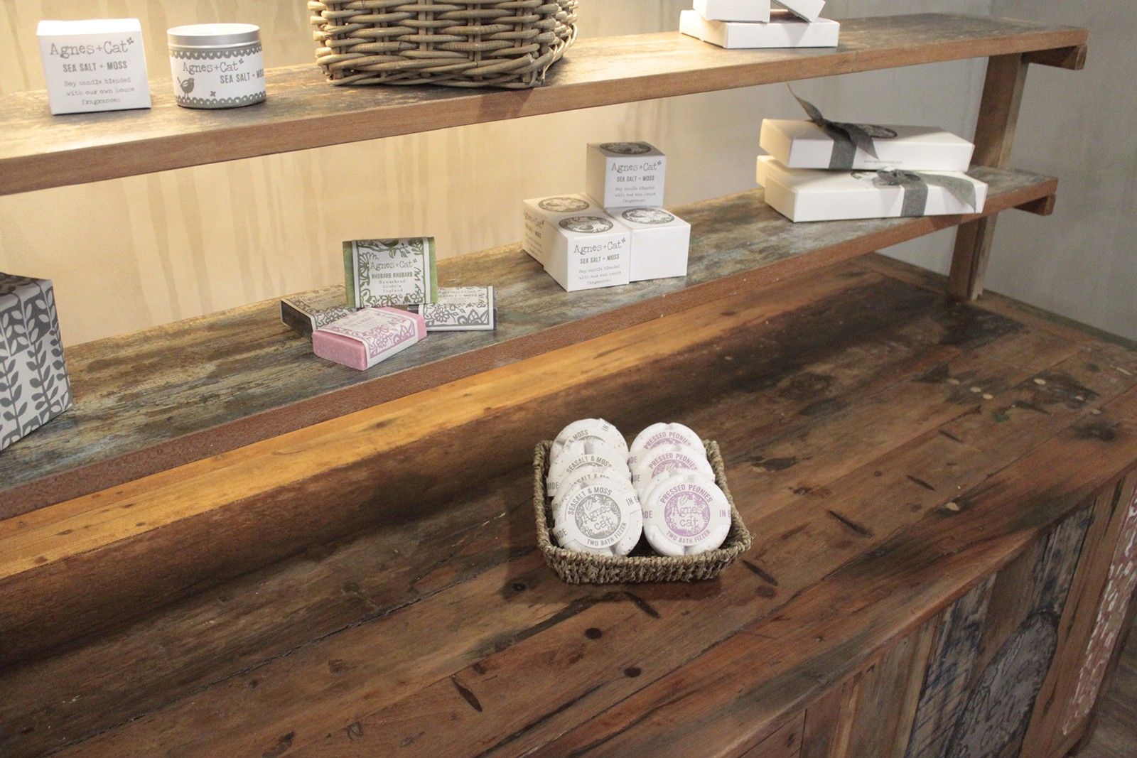 A woven basket with white soap bars placed on a recycled teak wood centre display table 207x97x80cm